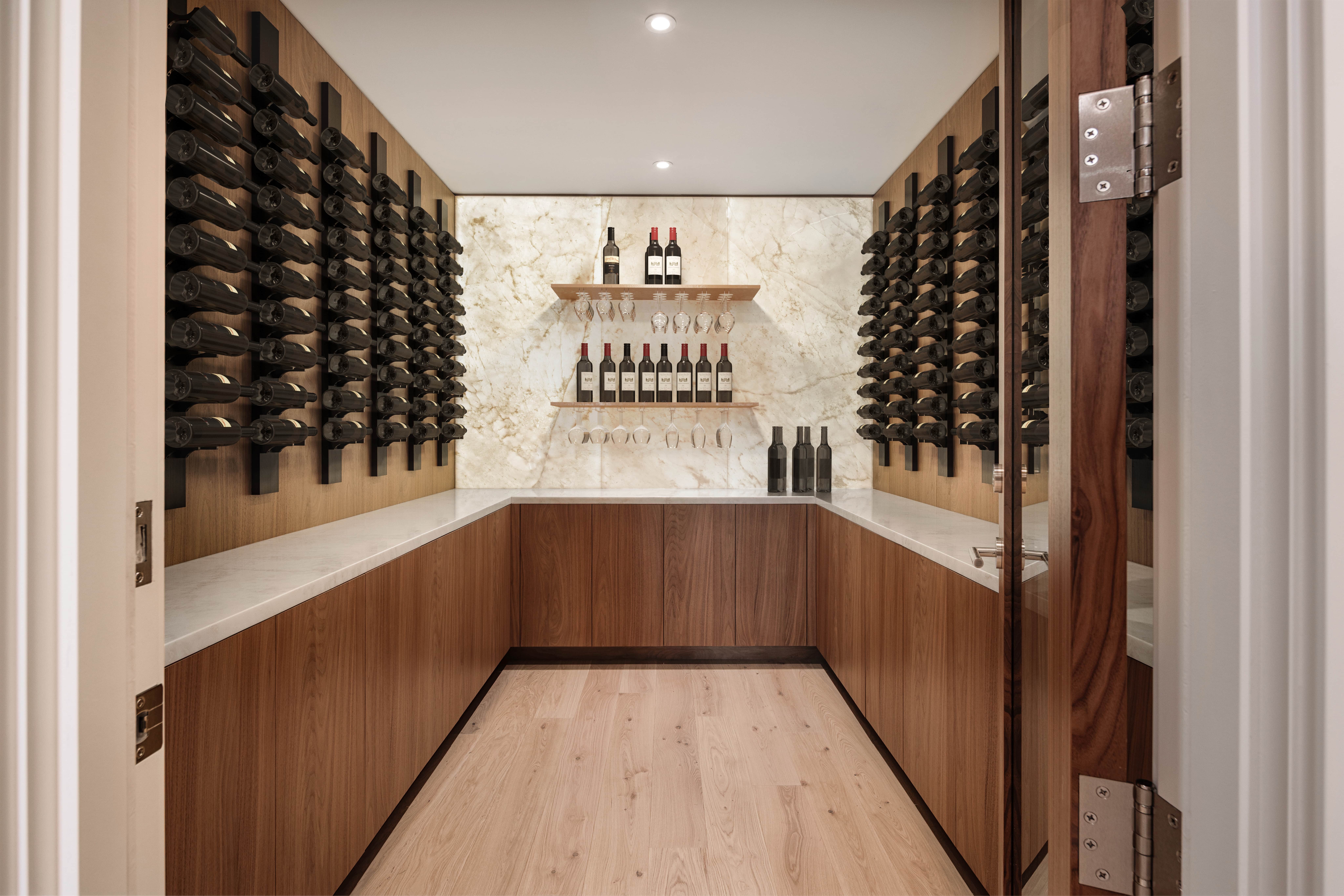 Wine cellar in Vancouver, BC, featuring wooden racks, marble wall, and bottles neatly arranged on shelves and countertops. Ideal for new construction or renovation projects.