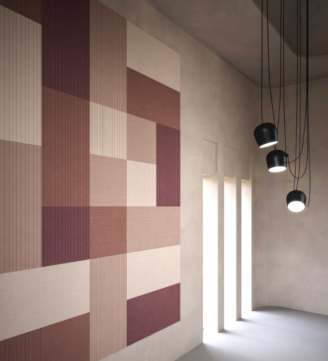 Geometric wall art in beige and maroon tones next to tall narrow windows and hanging black pendant lights.