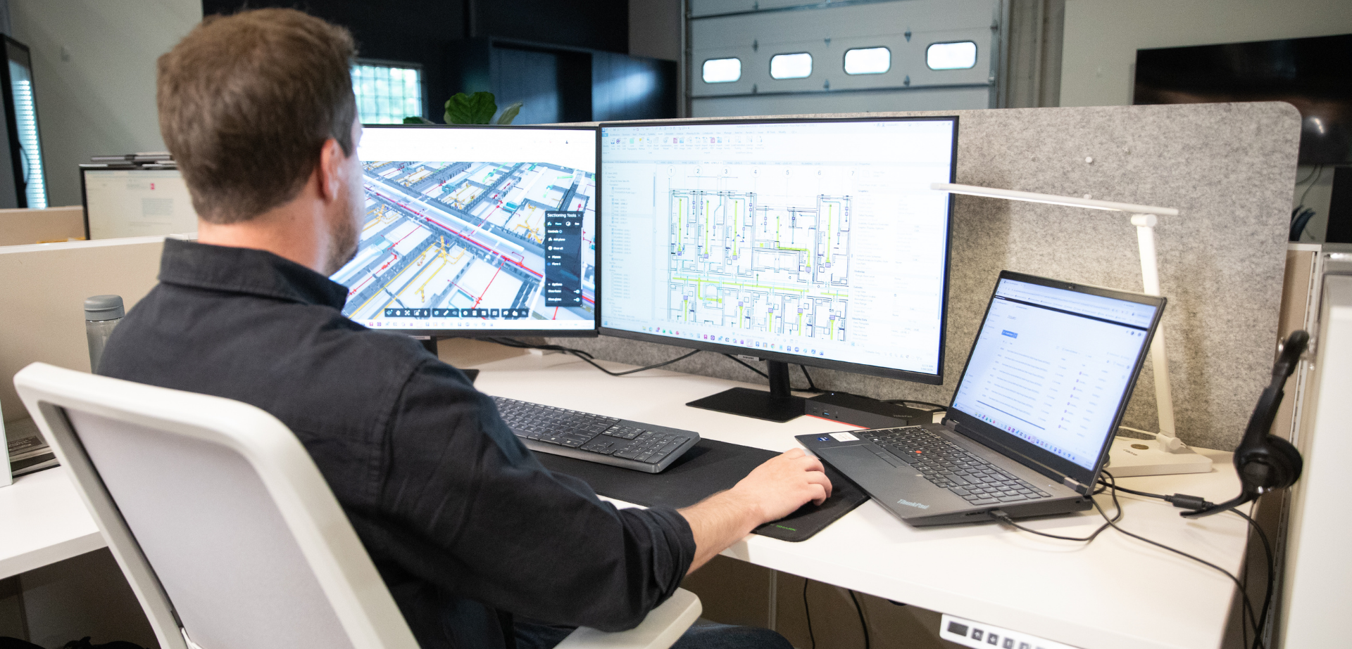 BIM team member reviewing a detailed 3D building model and technical construction drawings across multiple computer screens to support project coordination.